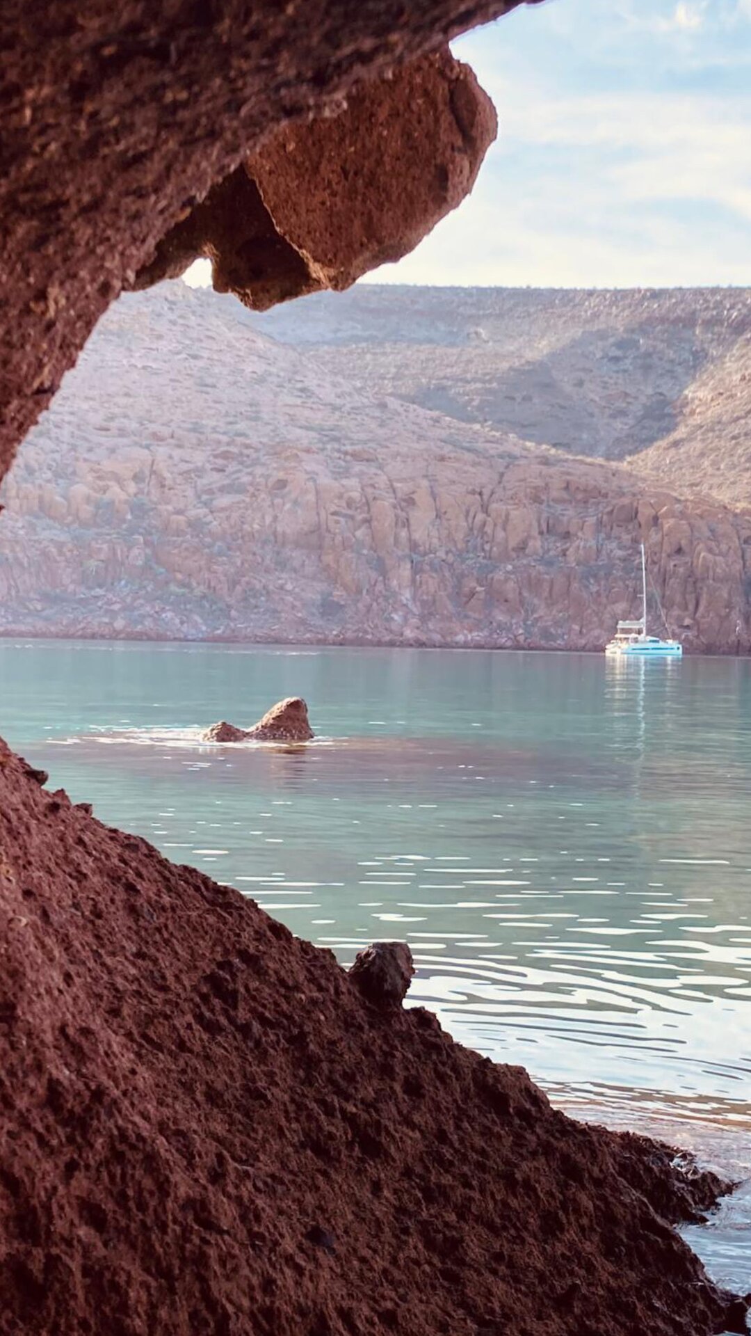 Private catamaran moored at a red-rock cove in Espíritu Santo, Sea of Cortez — BAIA Atelier